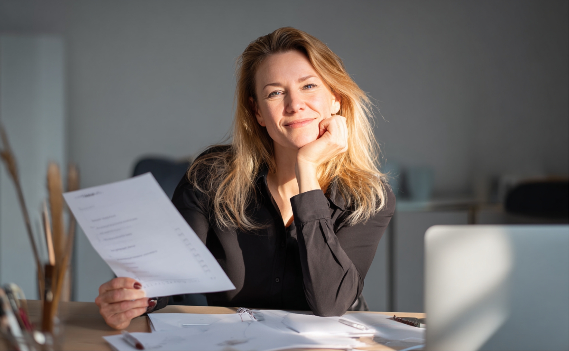 Frau am Schreibtisch mit Checkliste zur Steuerkanzlei-Wahl, Laptop und Notizbuch – ruhige, helle Büroszene bei Tageslicht