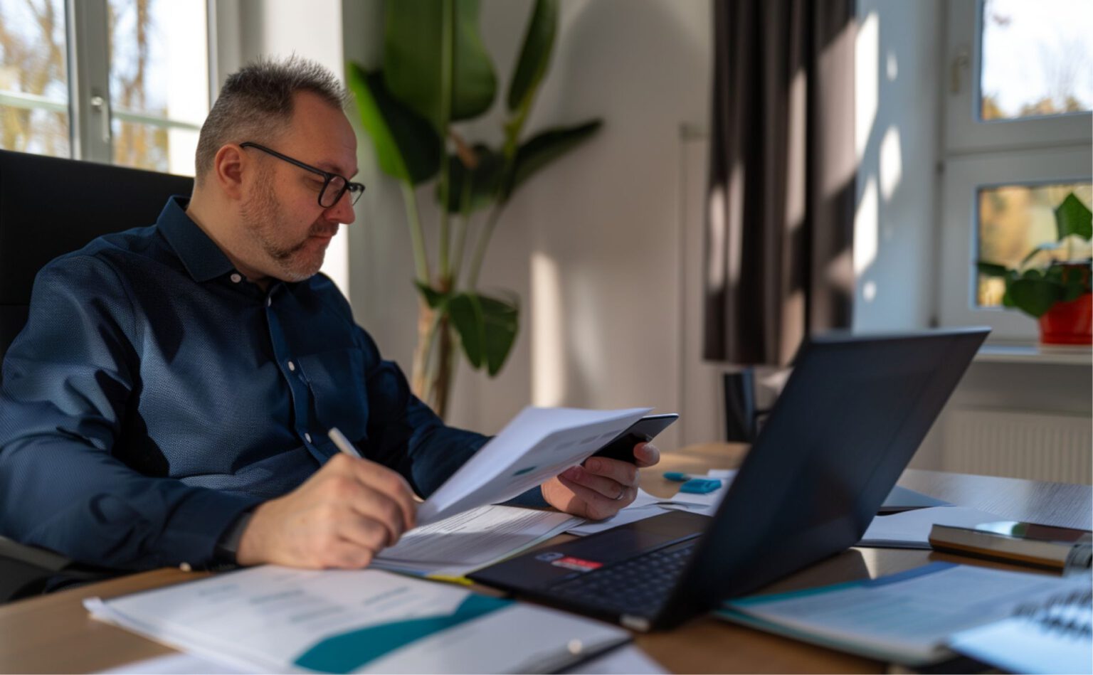 Geschäftsmann erfasst digitale Belege mit Smartphone und Laptop im modernen Steuerbüro von Goerke & Partner in Berlin